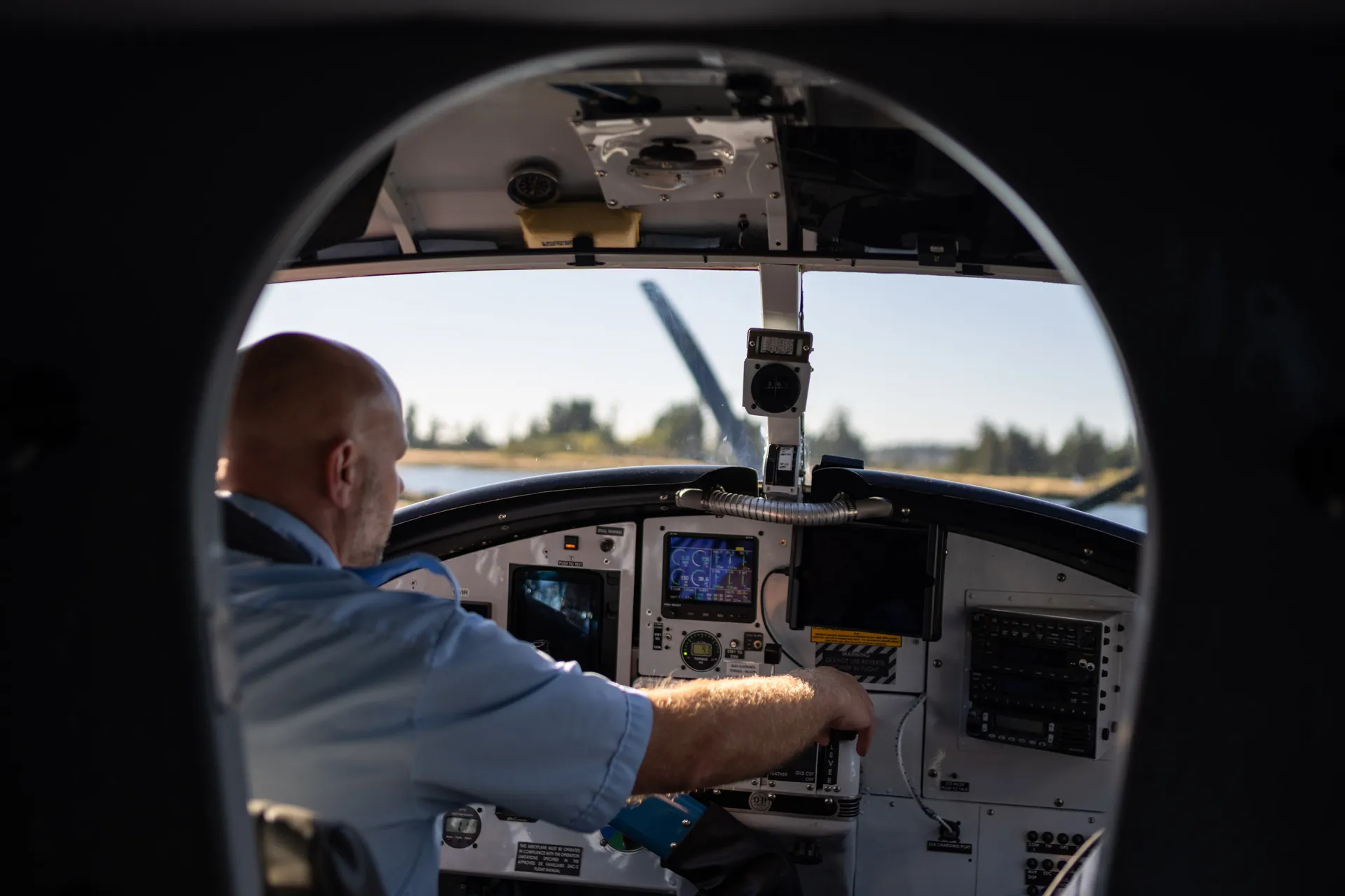 The floatplane cockpit from the cabin, the pilot's hand on the controls and the coast ahead