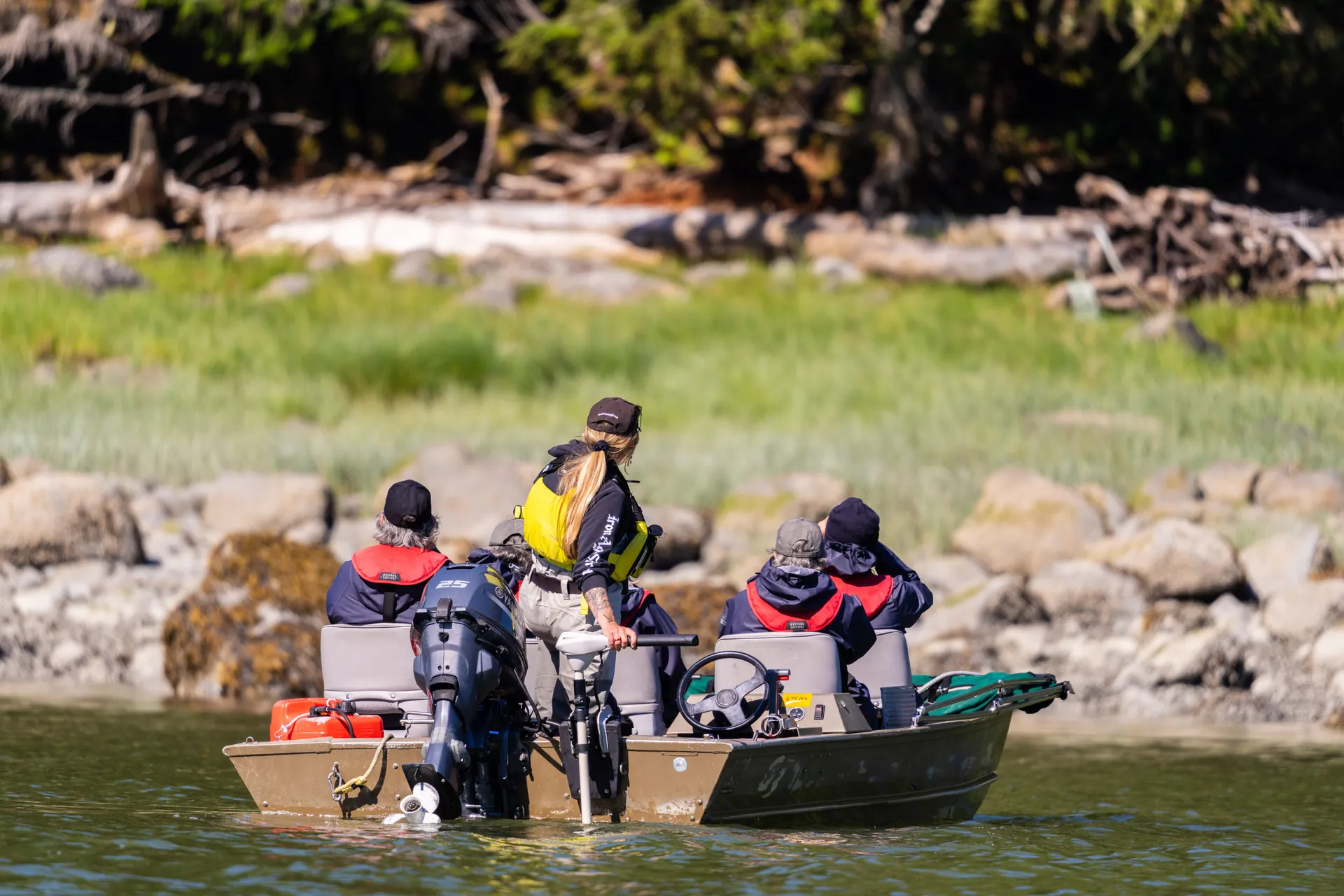 Guests in a boat a few metres off the rocky shore, cameras raised