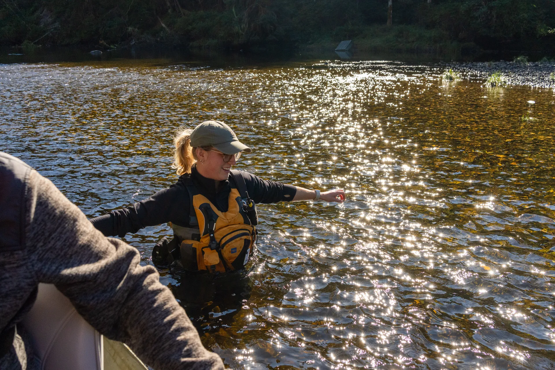A guide wading the shallows to walk the boat, the water lit gold behind him