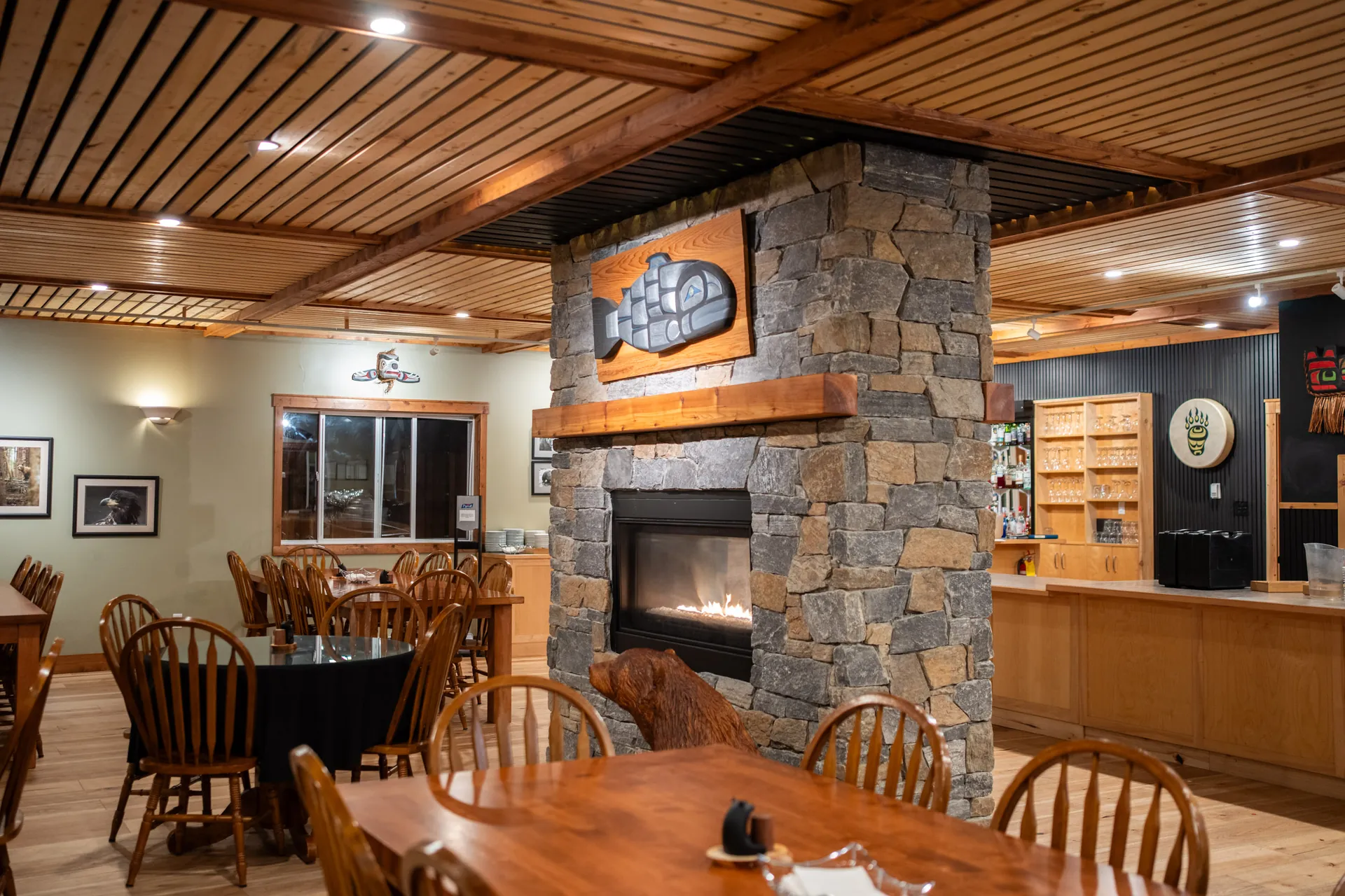 The lounge with its stone fireplace and the carved salmon above, tables and chairs