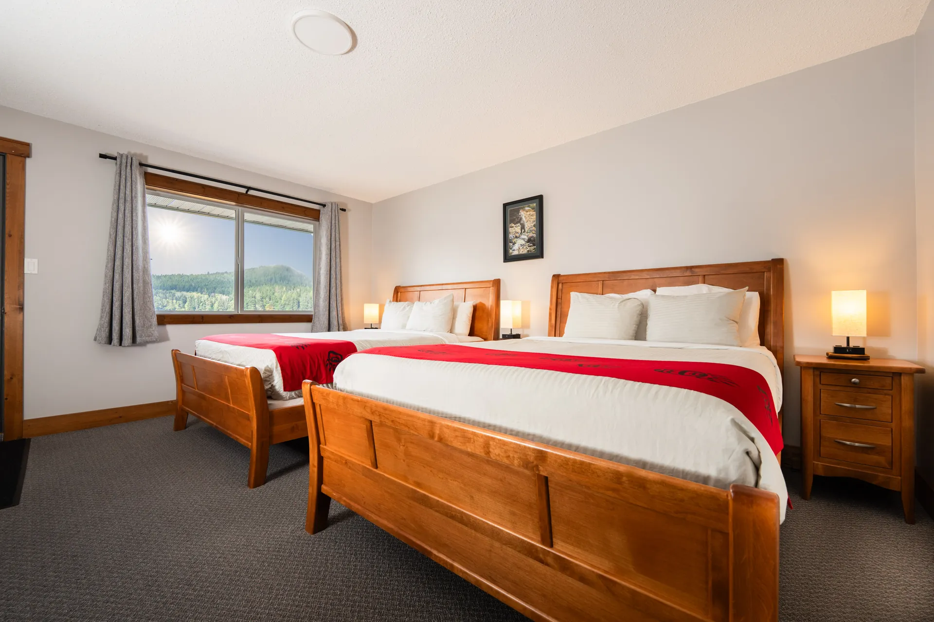 A guest room, a timber bed with a red blanket and the cove through the window