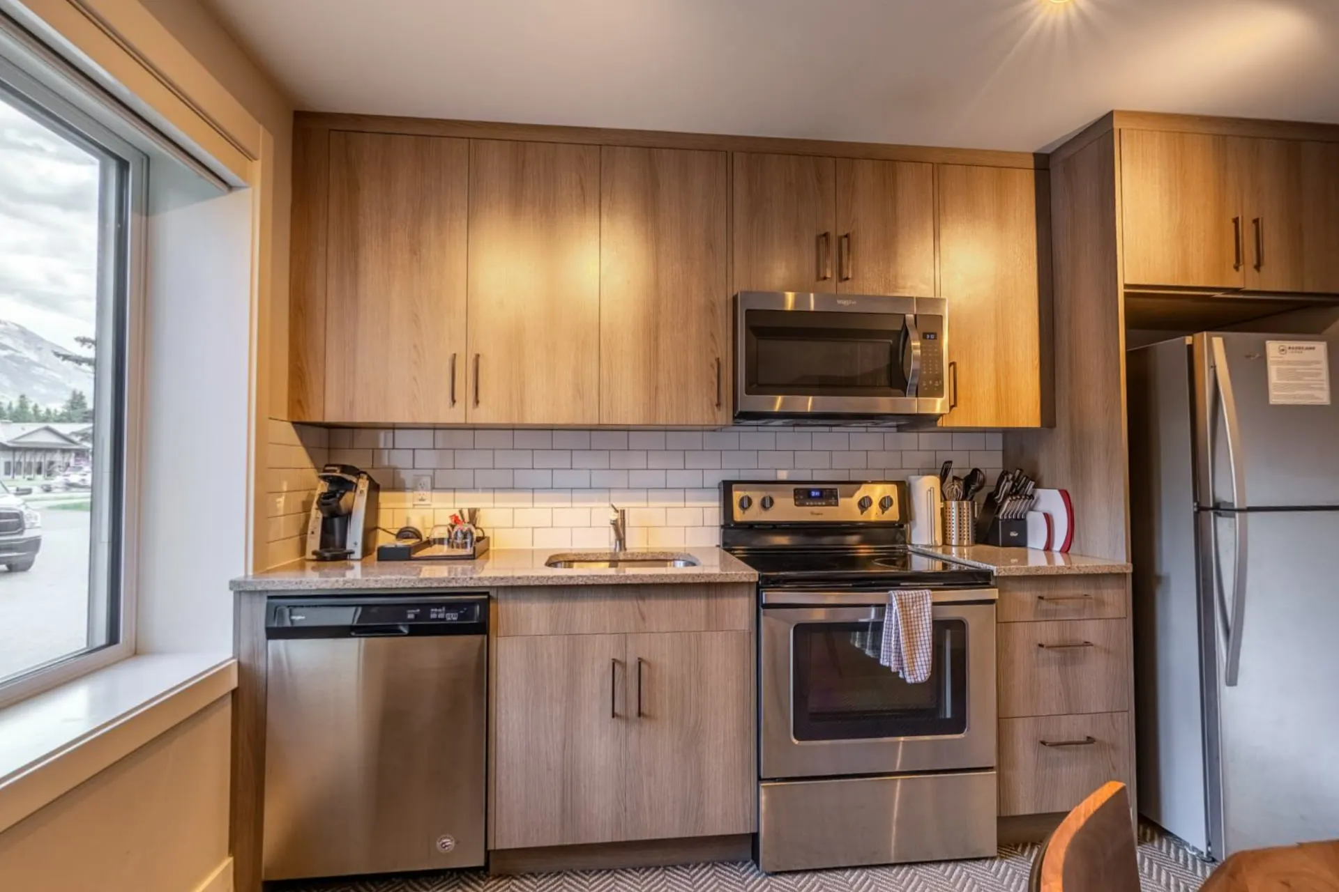 The micro suite's kitchen with timber cabinets, stainless appliances and a window to the street