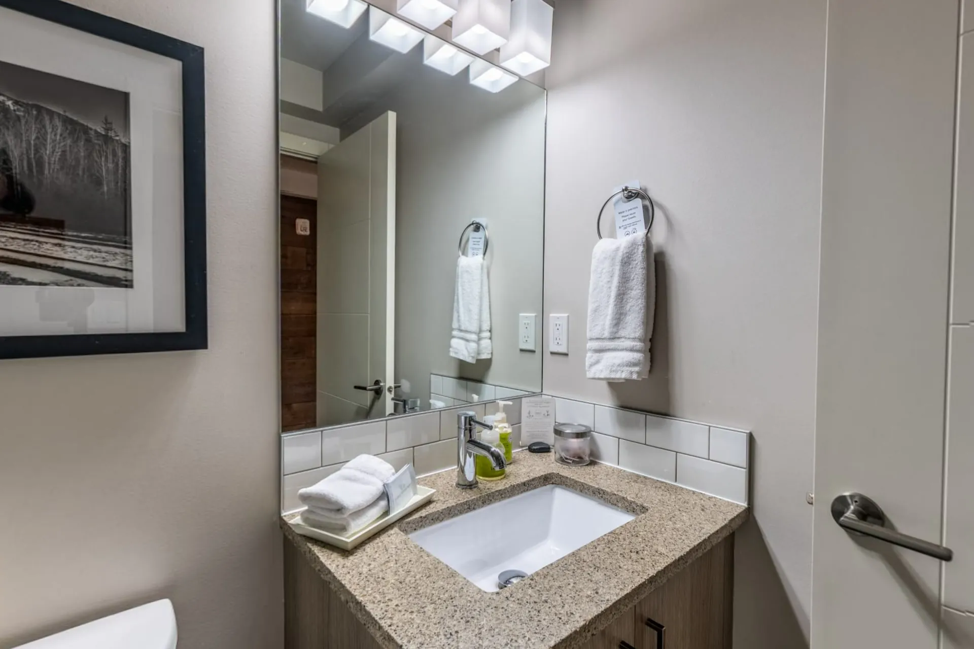 A bathroom with a vanity, folded towels and a mountain photograph