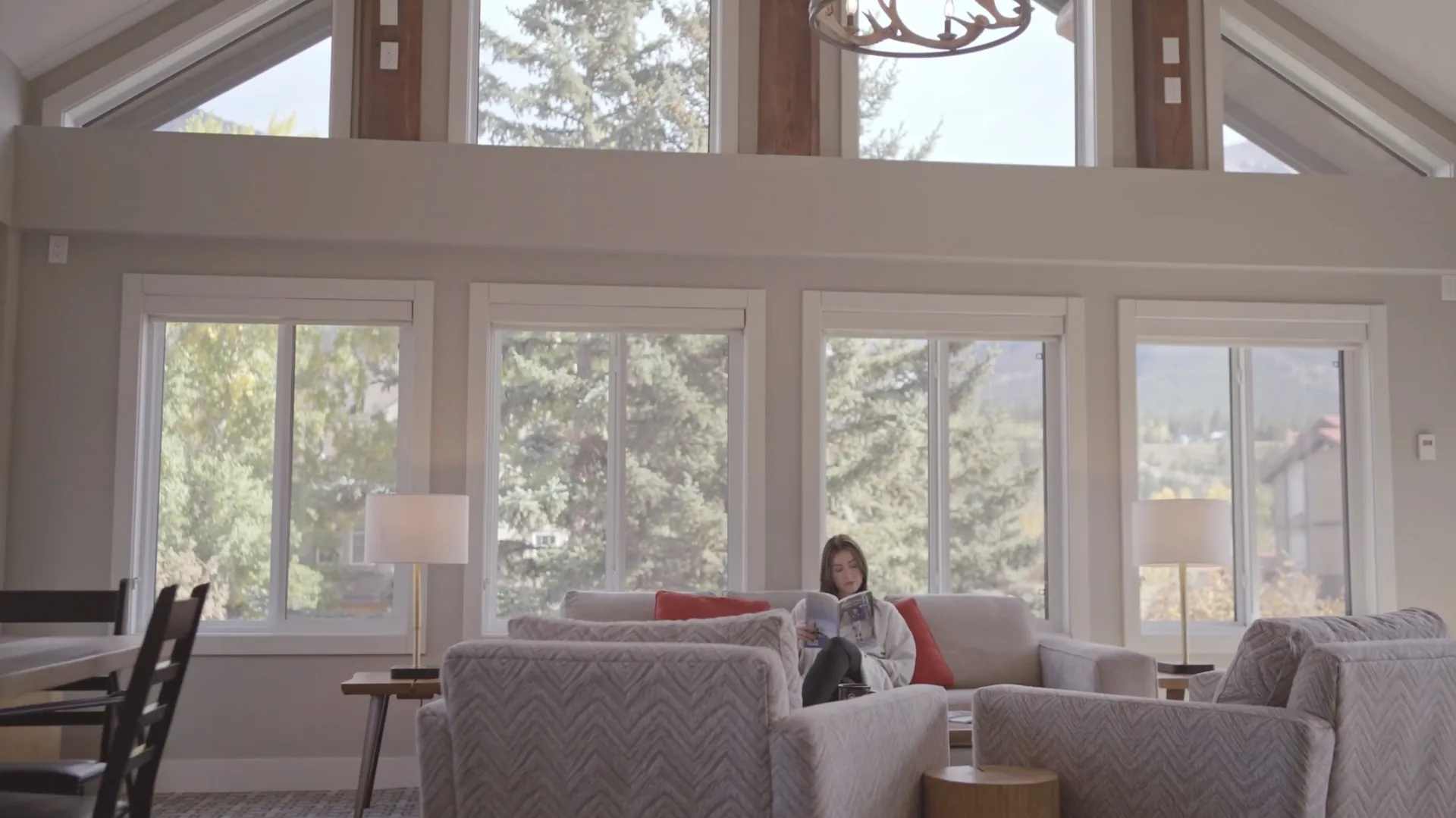 Reading in a corner of the great room, the vaulted ceiling and the windows full of trees