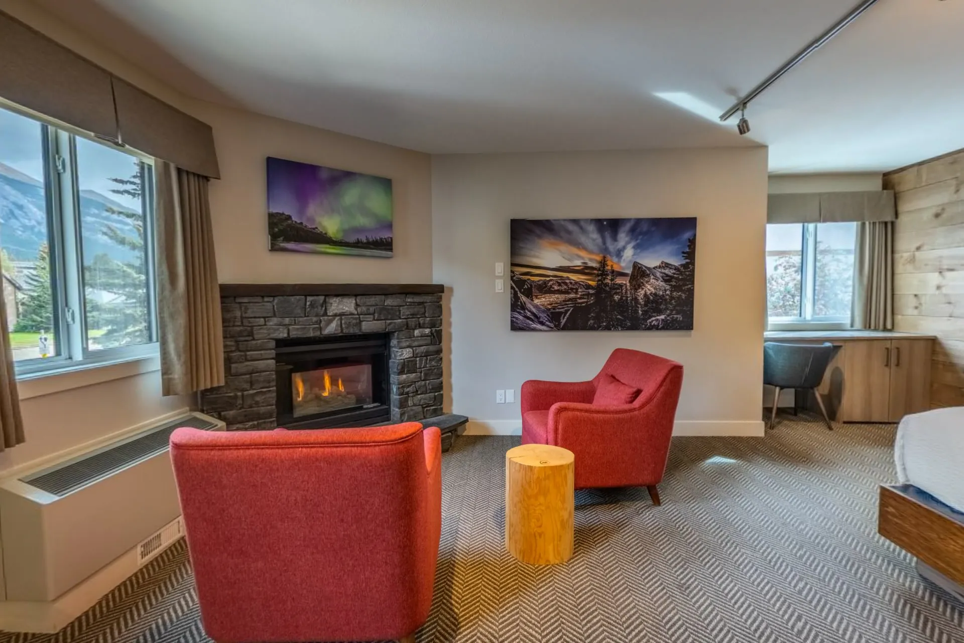 The king suite's sitting area, two red armchairs by a gas fireplace and aurora prints on the wall