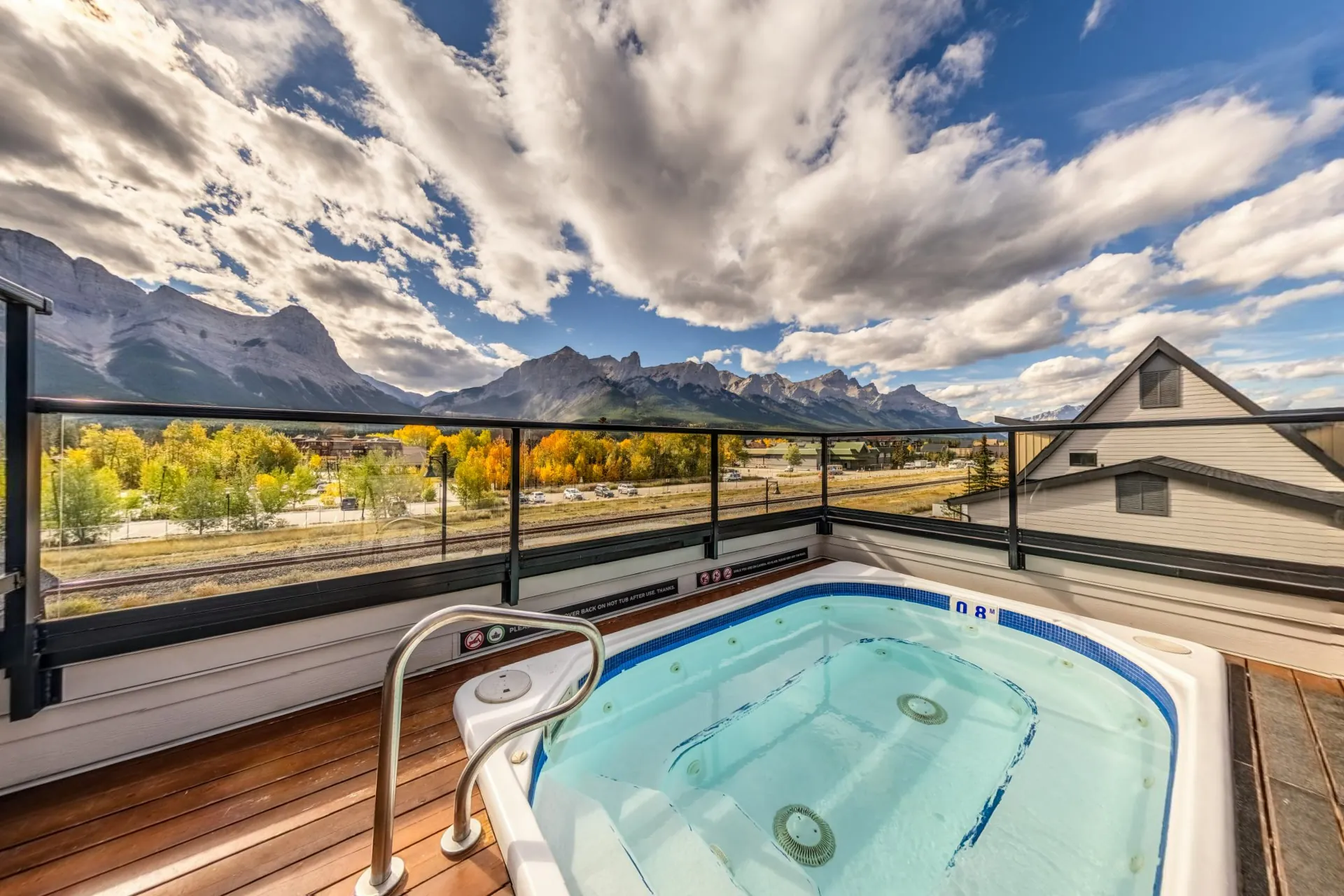 The rooftop hot tub at Basecamp Resorts Canmore, the Three Sisters and the Bow Valley peaks across the glass rail