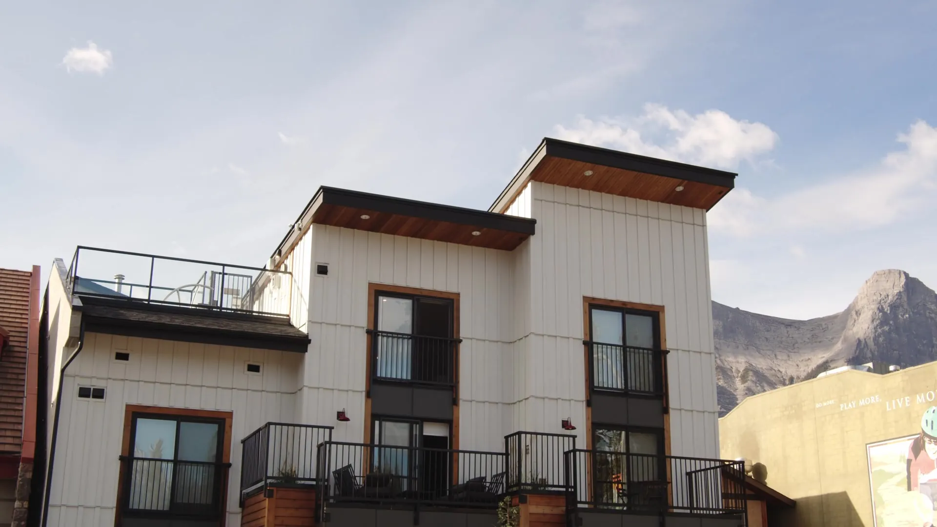 The white-clad suites with their rooftop deck against the mountainside, seen from the street