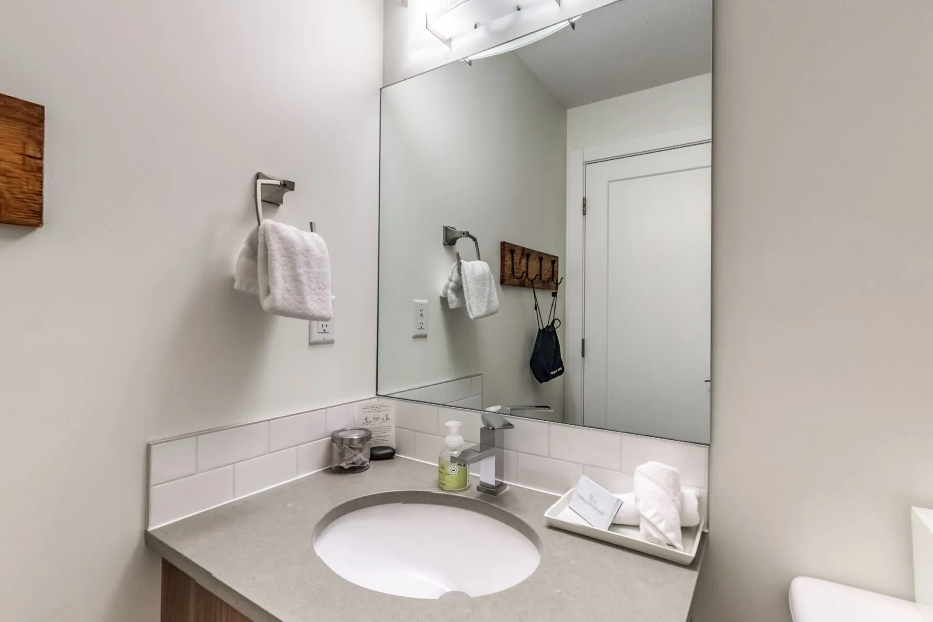 A white-tiled bathroom with a vanity, towels and toiletries laid out
