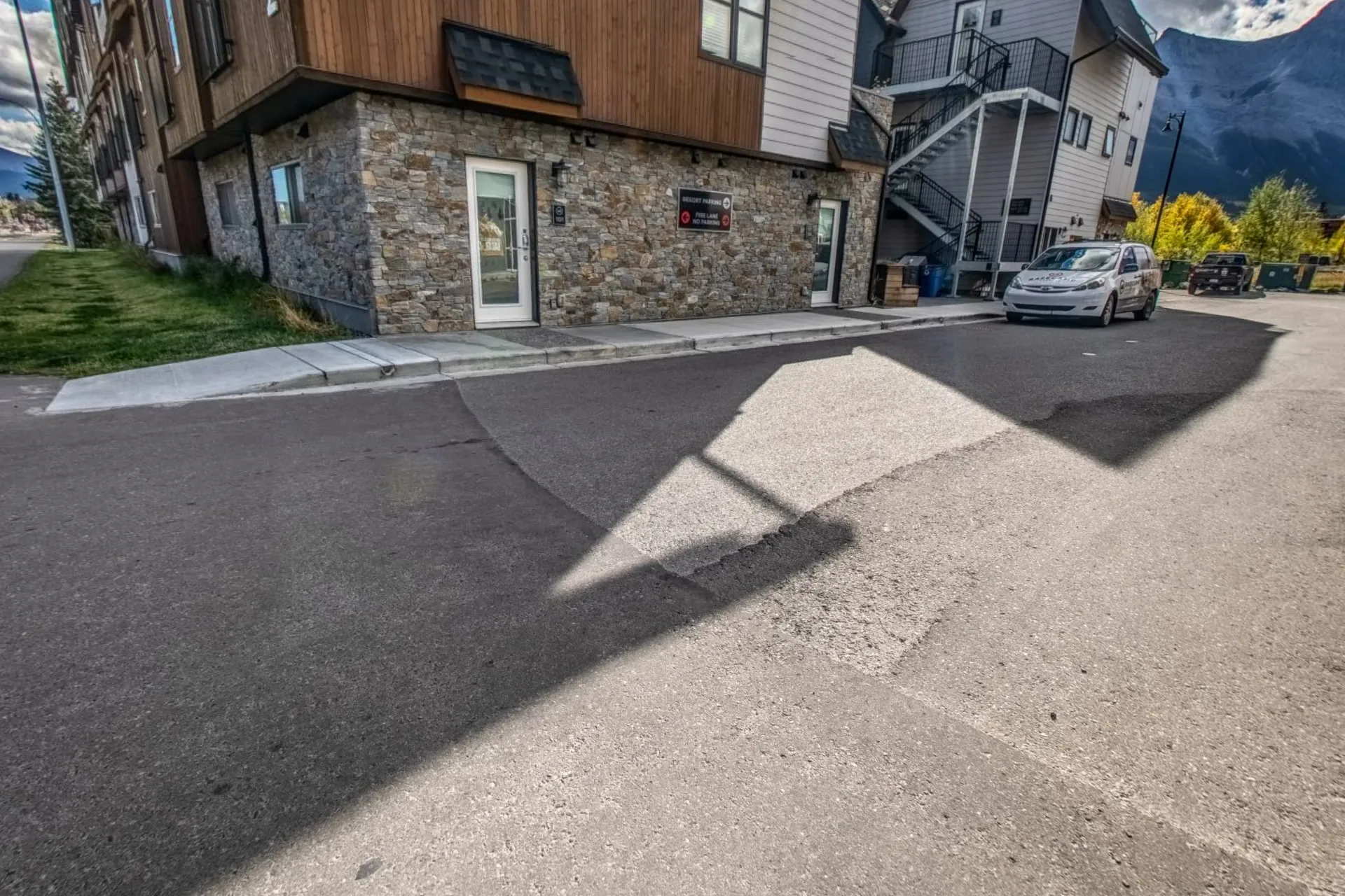 The lane beside the suites with the stone-clad entry and the mountains at the end of the street