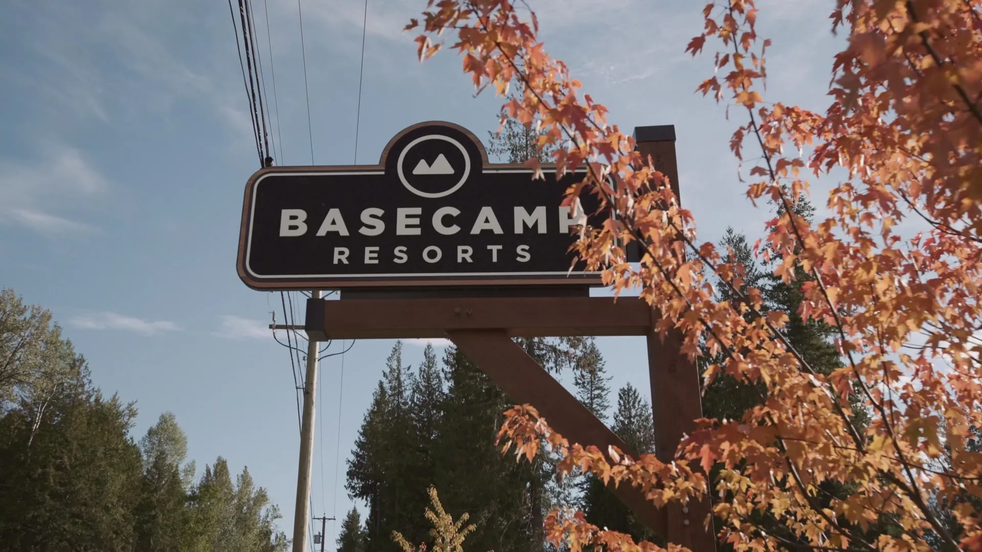 The Basecamp Resorts sign among autumn maples against a blue sky