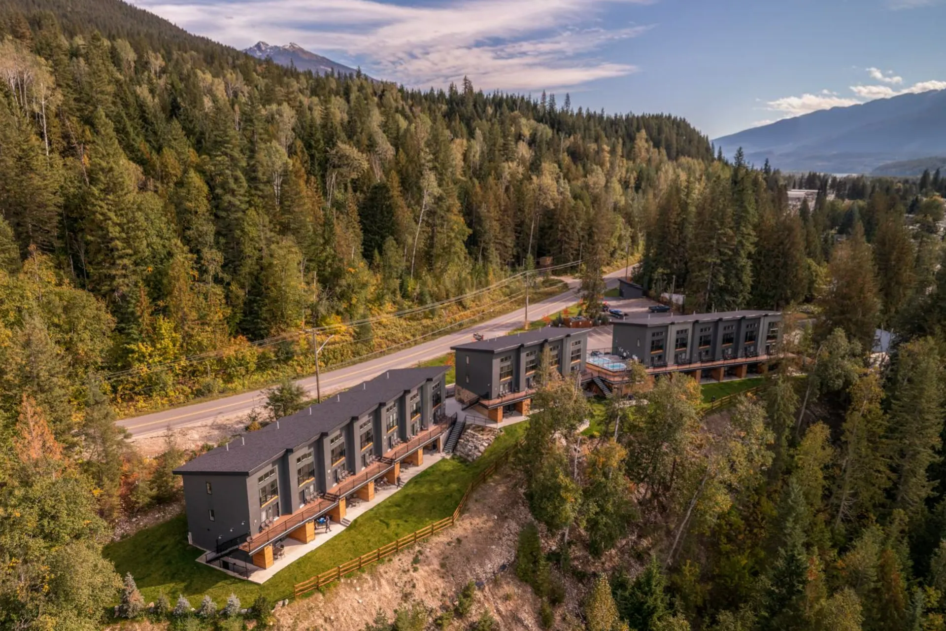 Basecamp Resorts Revelstoke from the air, the three-storey suites on a forested bluff above the Columbia River, Highway 23 behind them