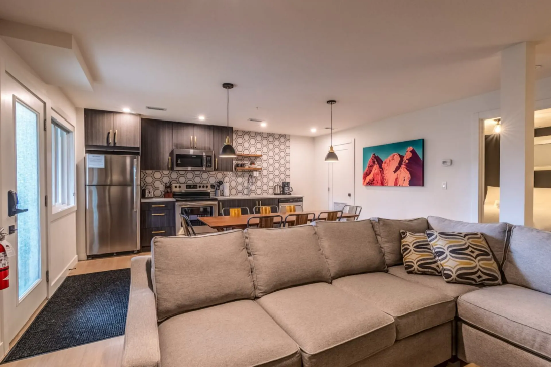 A ground-floor living area, a large sectional, the open kitchen and a door out to the lawn