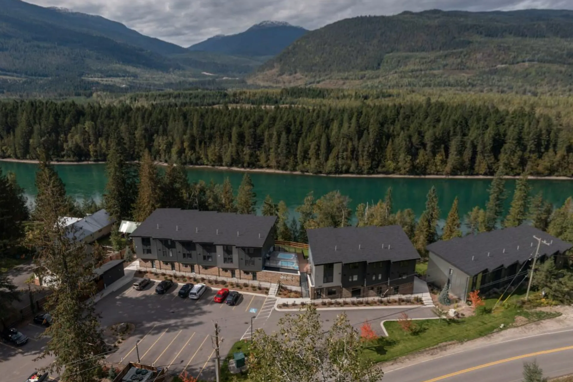 The full property from above, the suites and their parking court beside the turquoise Columbia River and the forested valley