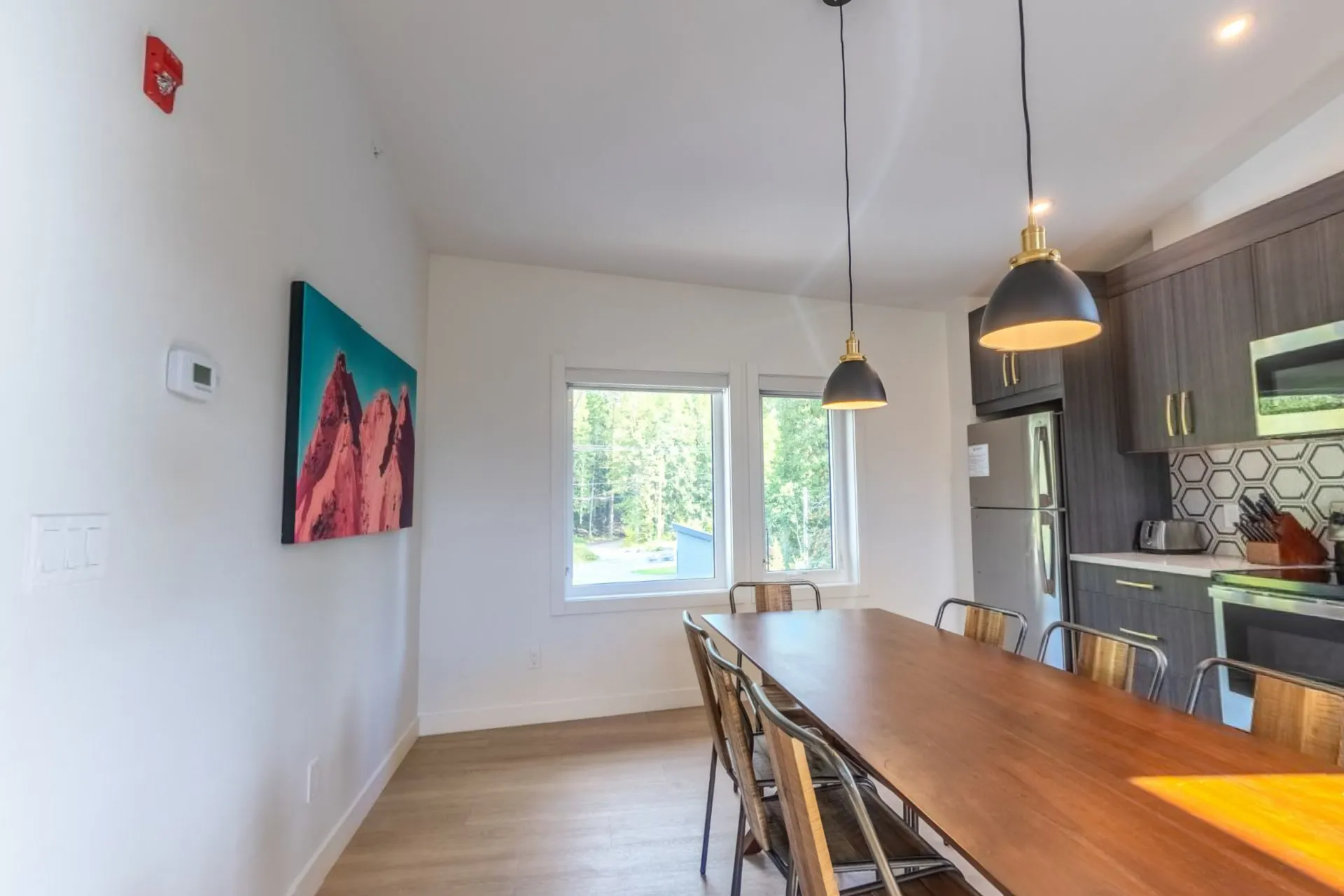 The three-bedroom suite's dining table for ten beside the kitchen, mountain artwork on the wall and a window to the trees