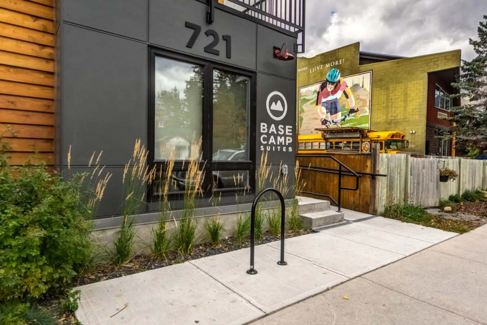 The street entrance with the 721 number, grasses along the path and a mural across the road