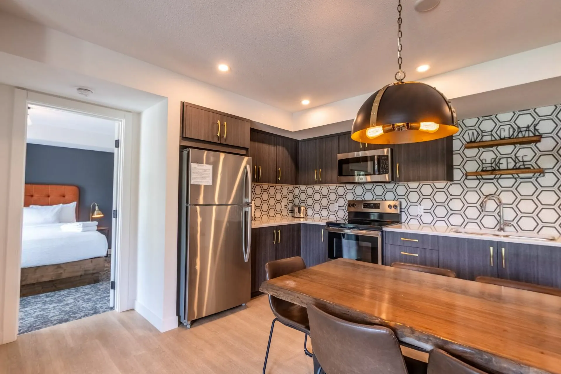 A three-bedroom apartment's kitchen and dining table, a bedroom through the open door