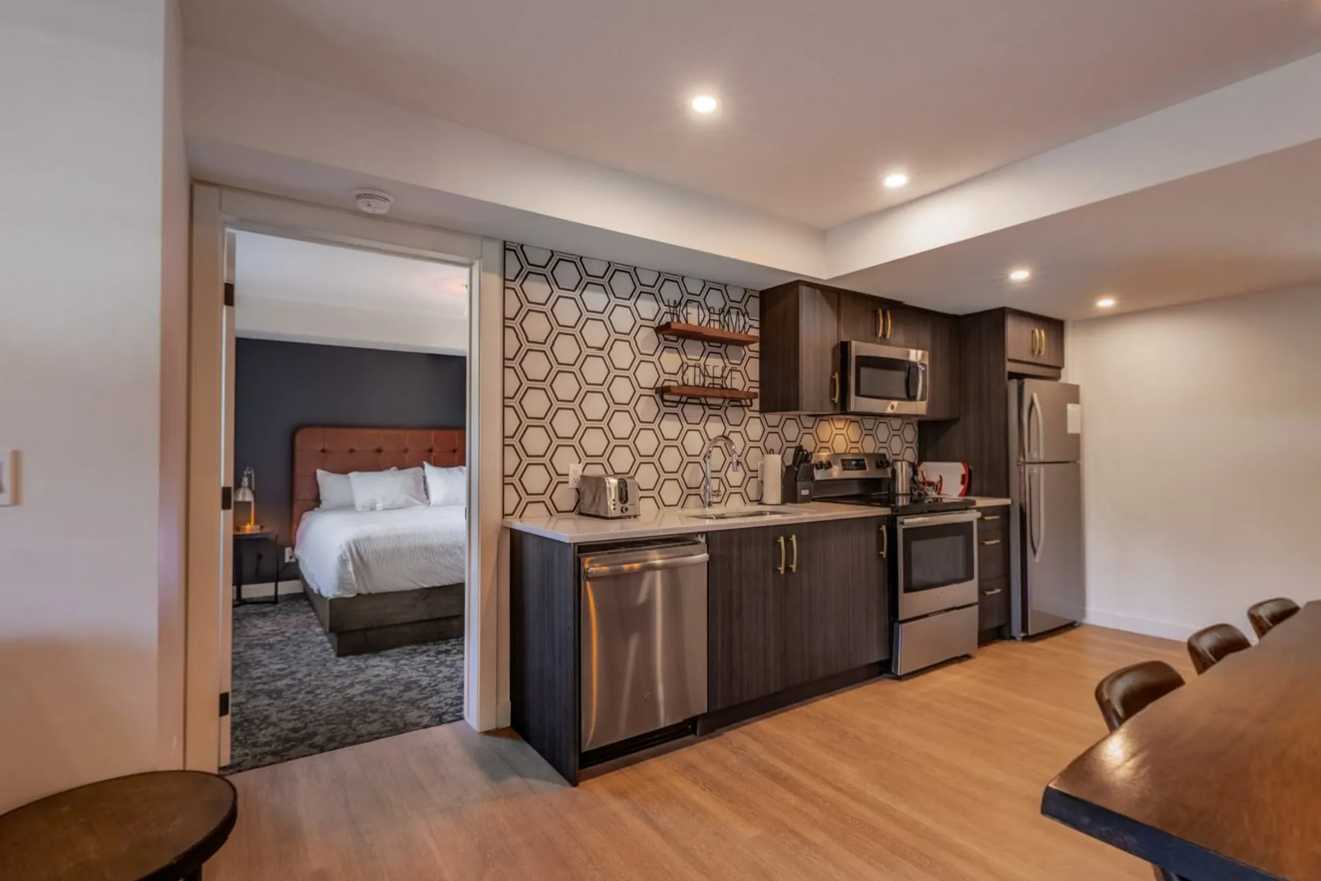 A two-bedroom suite's living area with the kitchen and a bedroom through the doorway