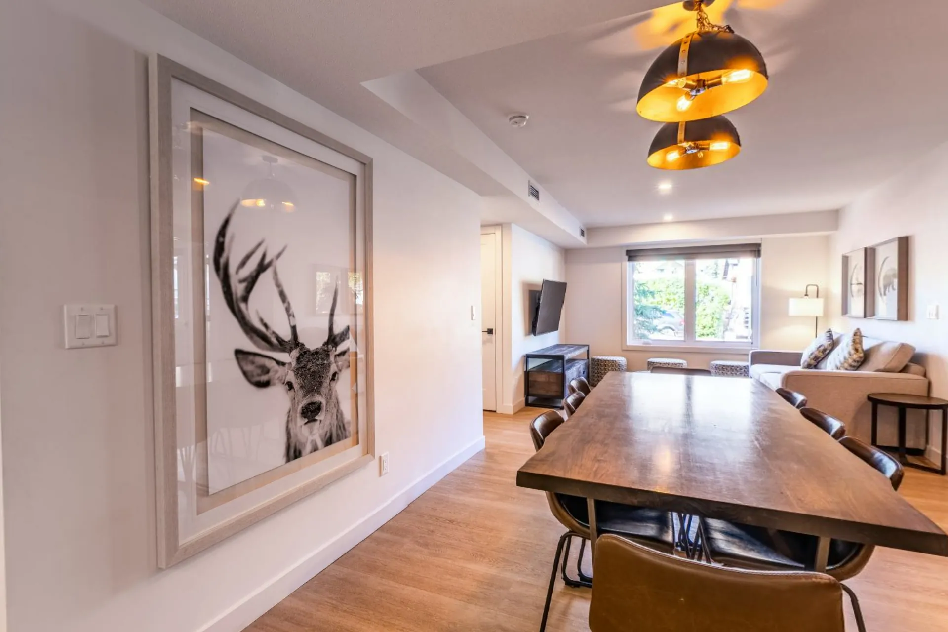 The dining area with a stag print on the wall and the living room behind