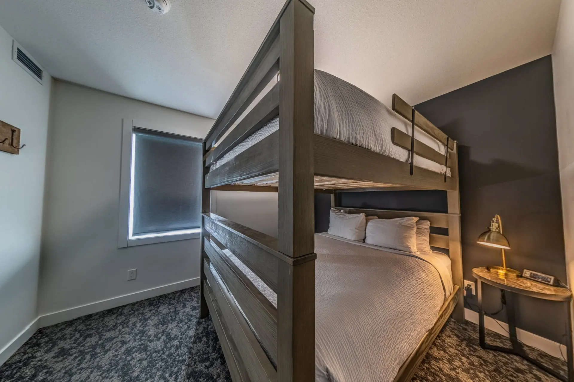 The bunk room of the three-bedroom with bunk apartment, timber bunks and a small window
