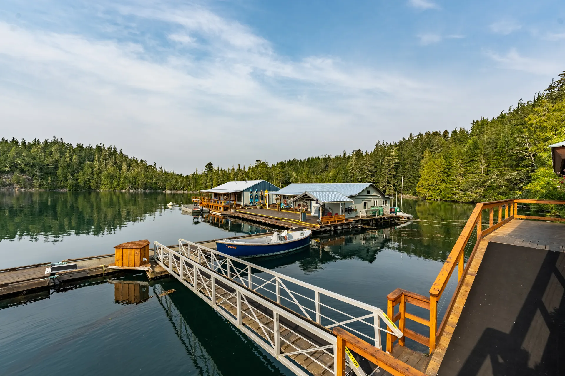 The floating guest rooms and dock from the deck, a guide boat tied to the float and a metal ramp descending from the lodge