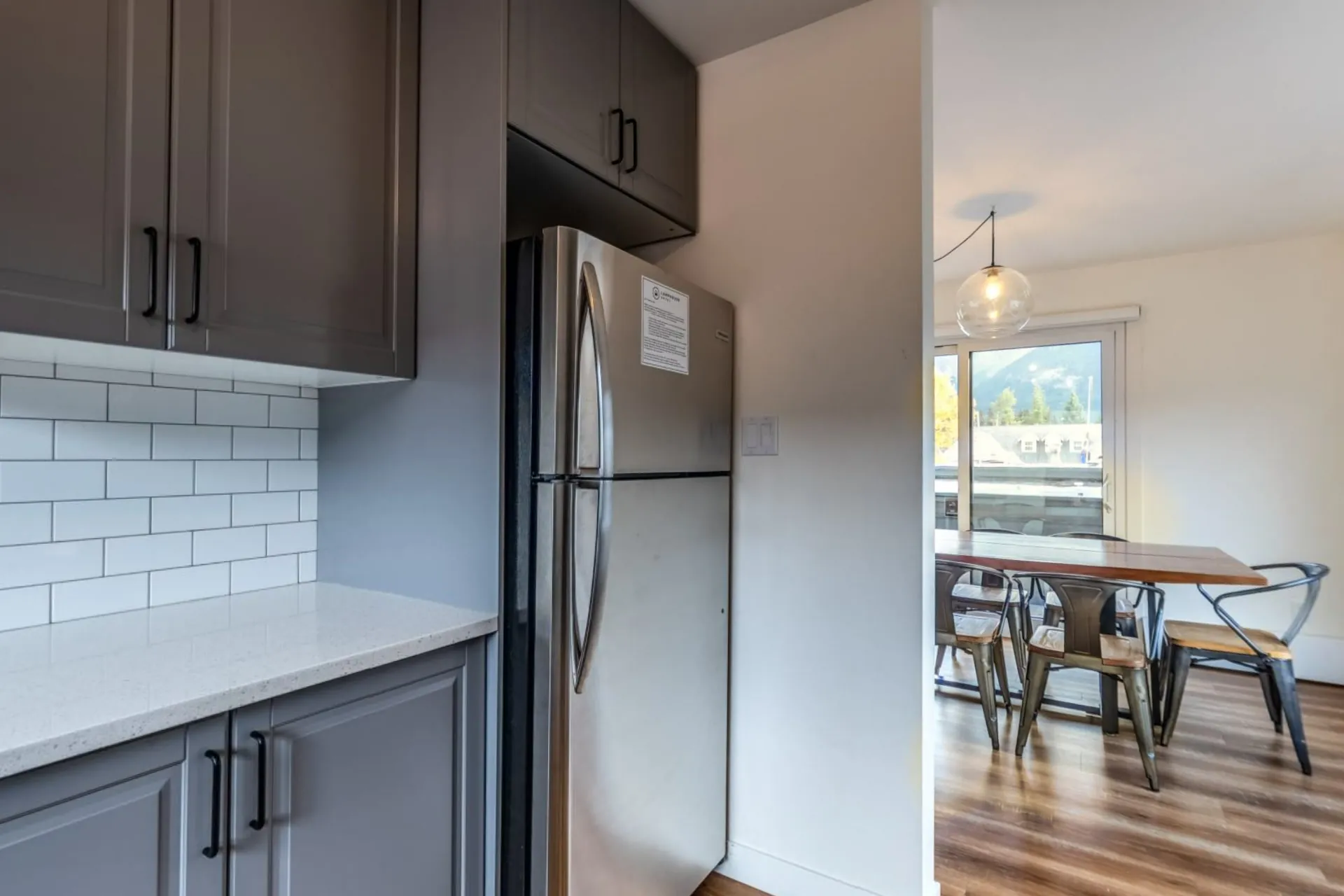 The apartment's kitchen with grey cabinets and a dining table by the window