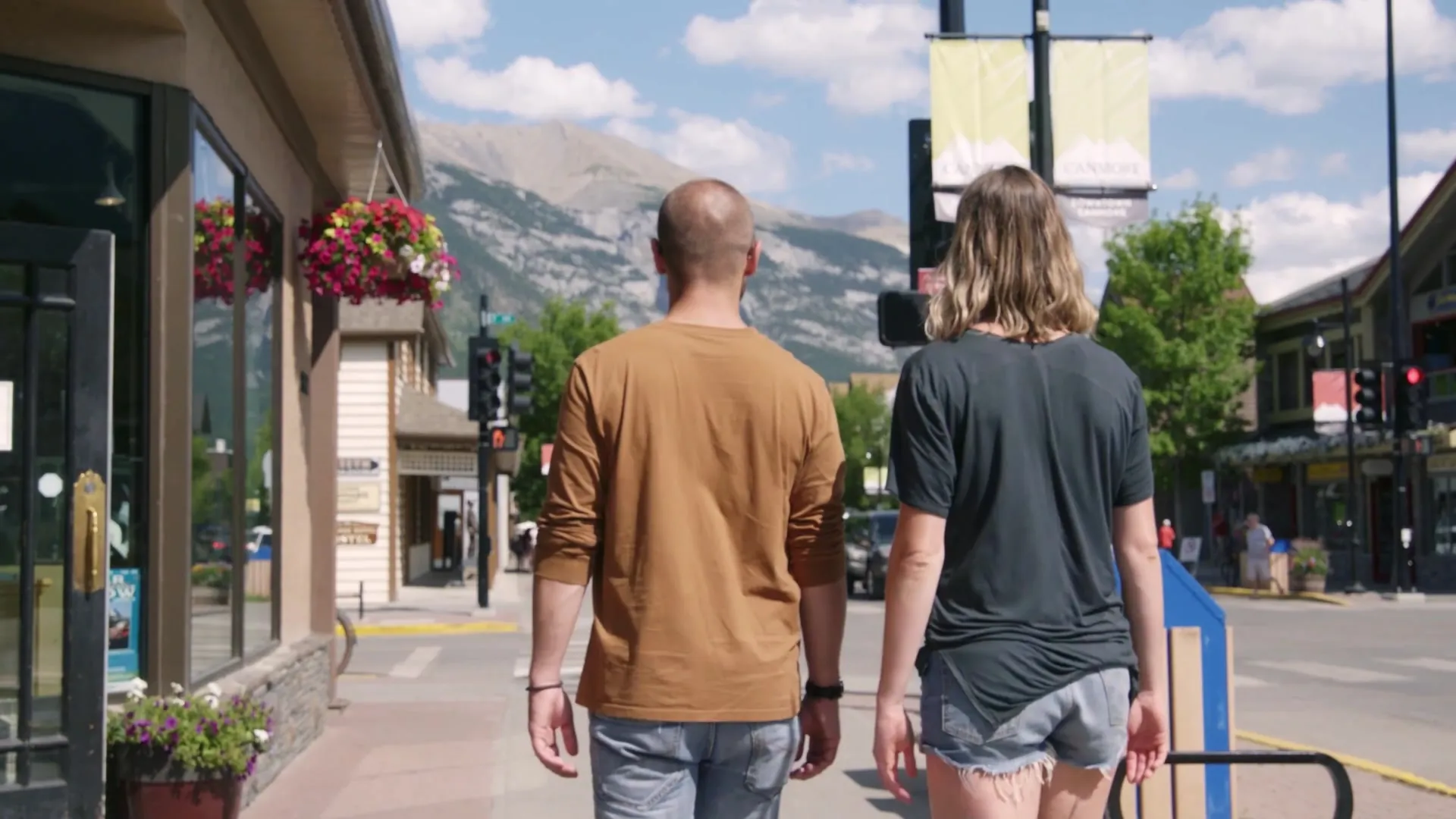 Two guests walking down Canmore's main street past the shops and flower baskets