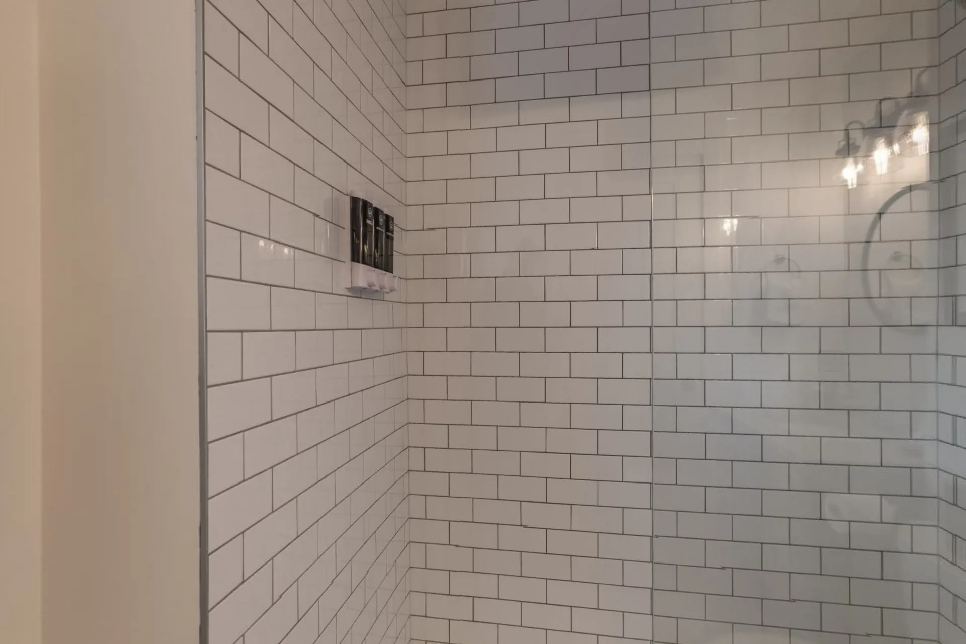 A white-tiled walk-in shower in a Lamphouse bathroom