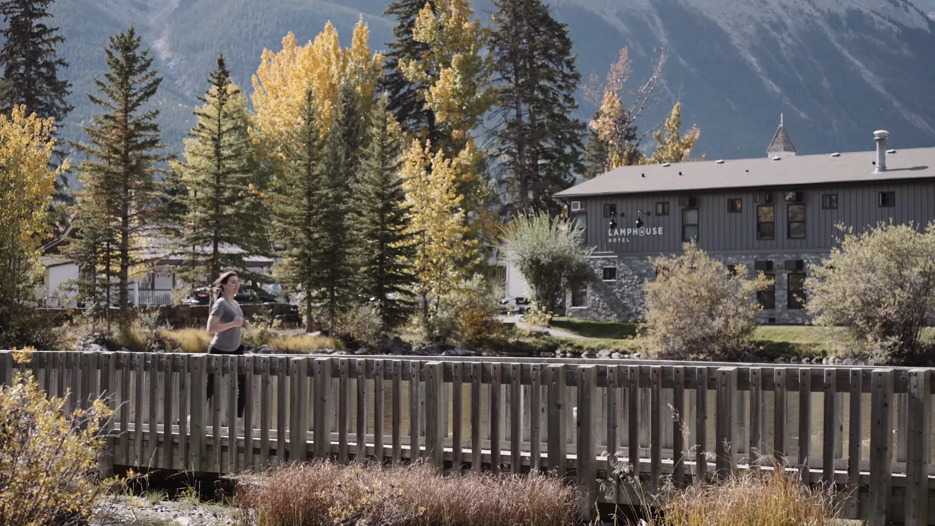 A guest crossing the footbridge over the creek towards Lamphouse, the hotel among the yellow aspens