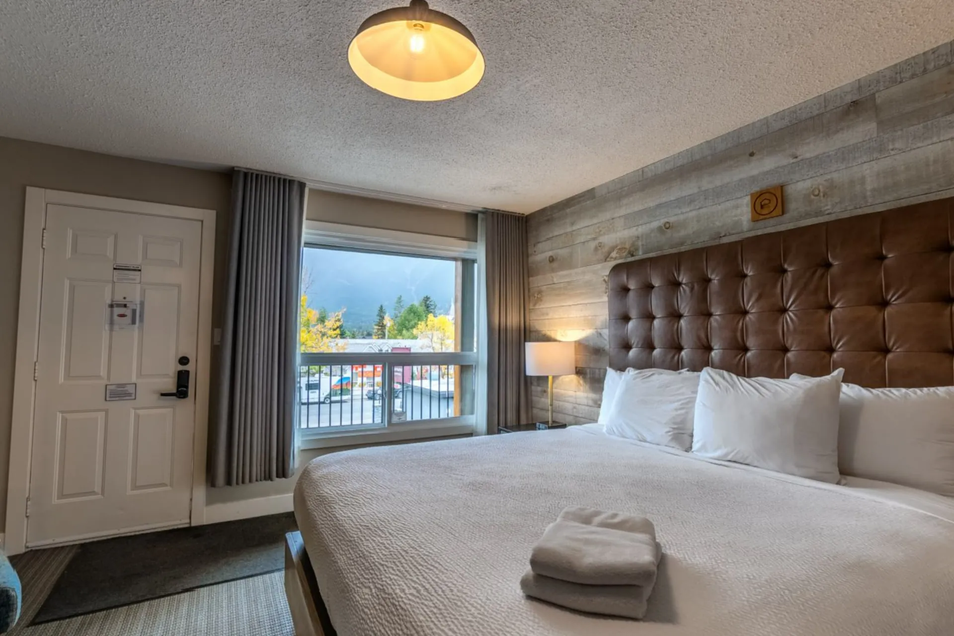 A king suite with a leather headboard and a window onto the peaks
