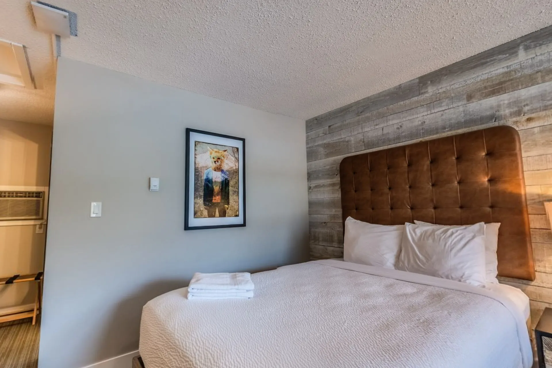 A double queen room with a timber feature wall and a mountain print