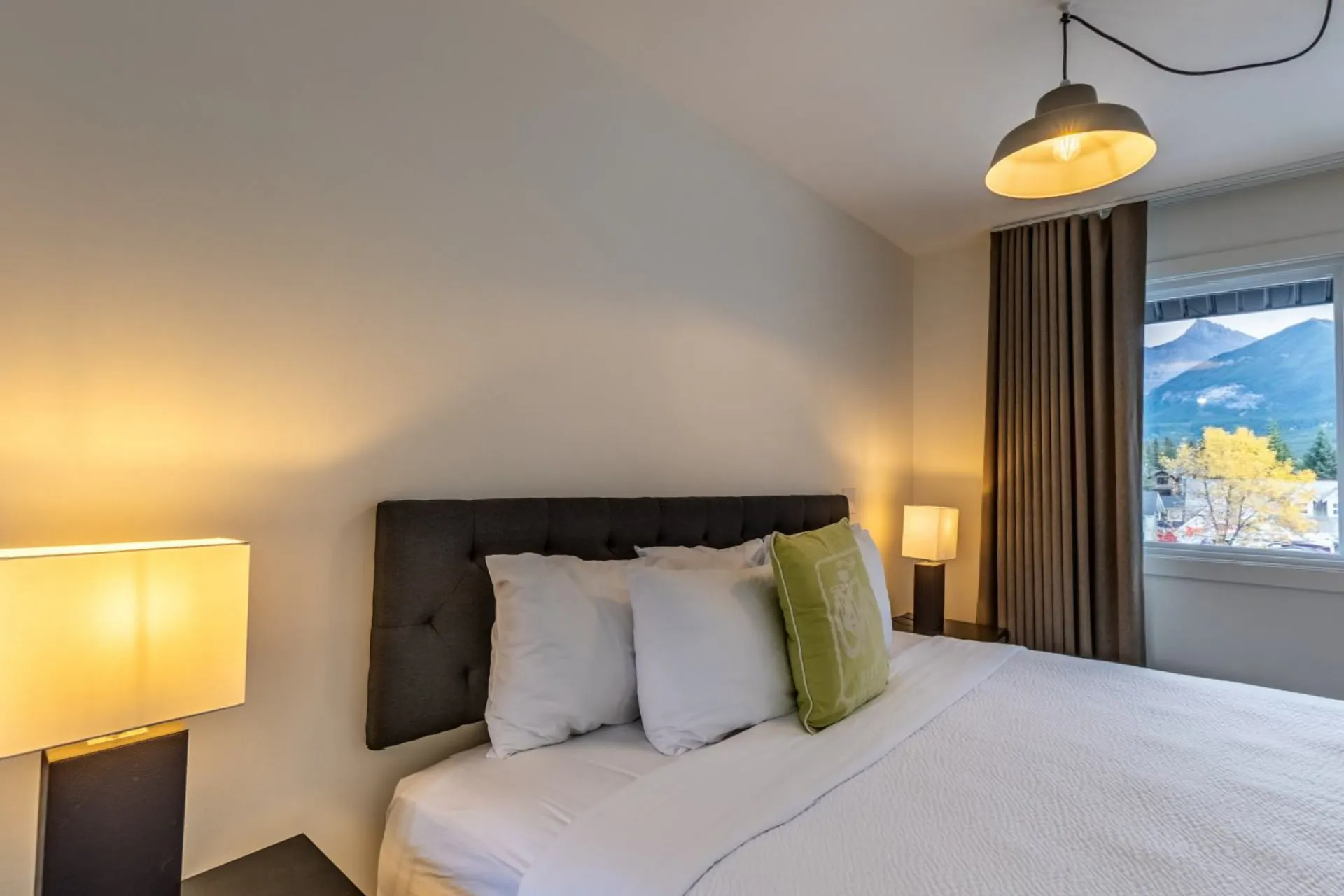 The Lamphouse Apartment's bedroom with a pendant light and mountains through the window