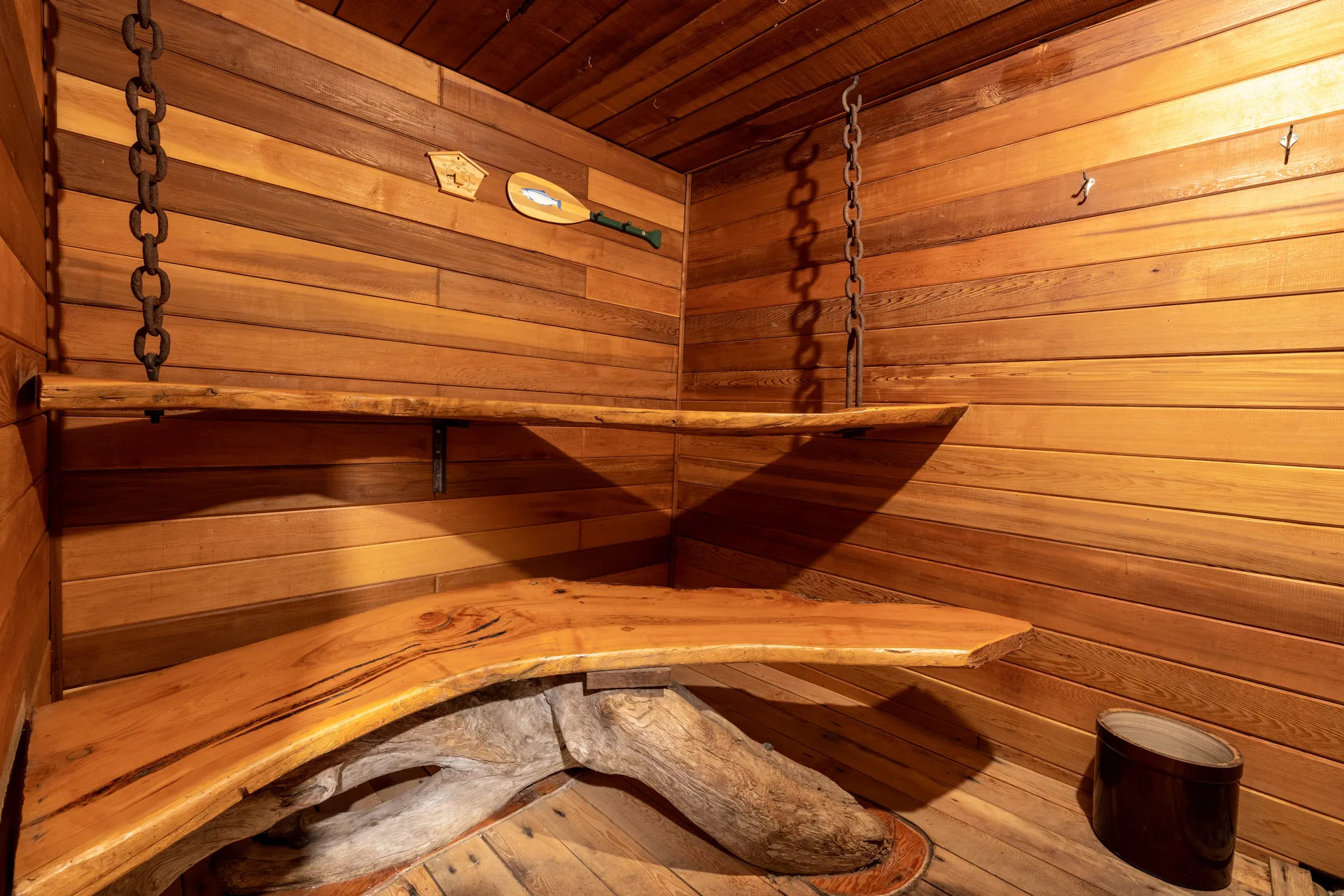 The cedar sauna interior with a curved wooden bench and hooks on the wall
