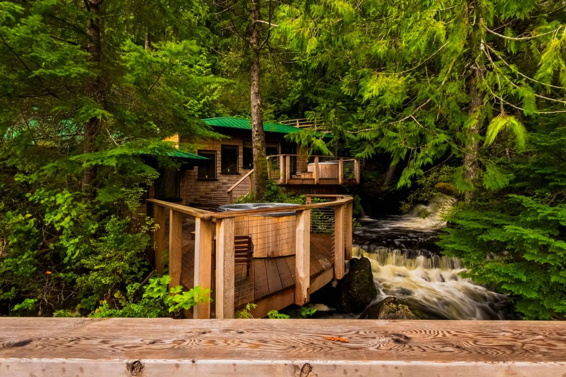 The spa building among the trees beside the creek, a boardwalk crossing the rushing water