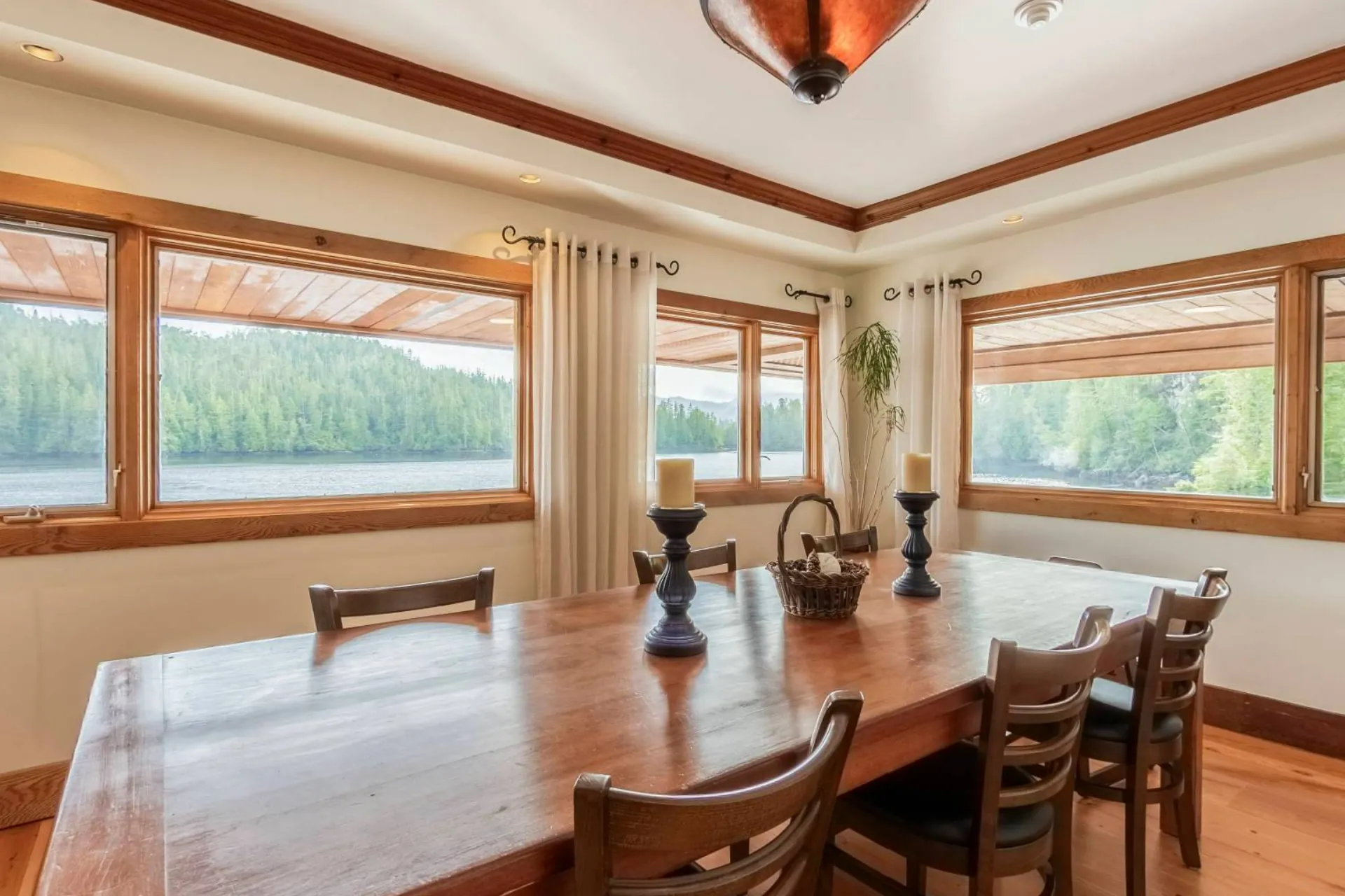 A dining table by the windows of a guest room, the bay and the far shore through the glass
