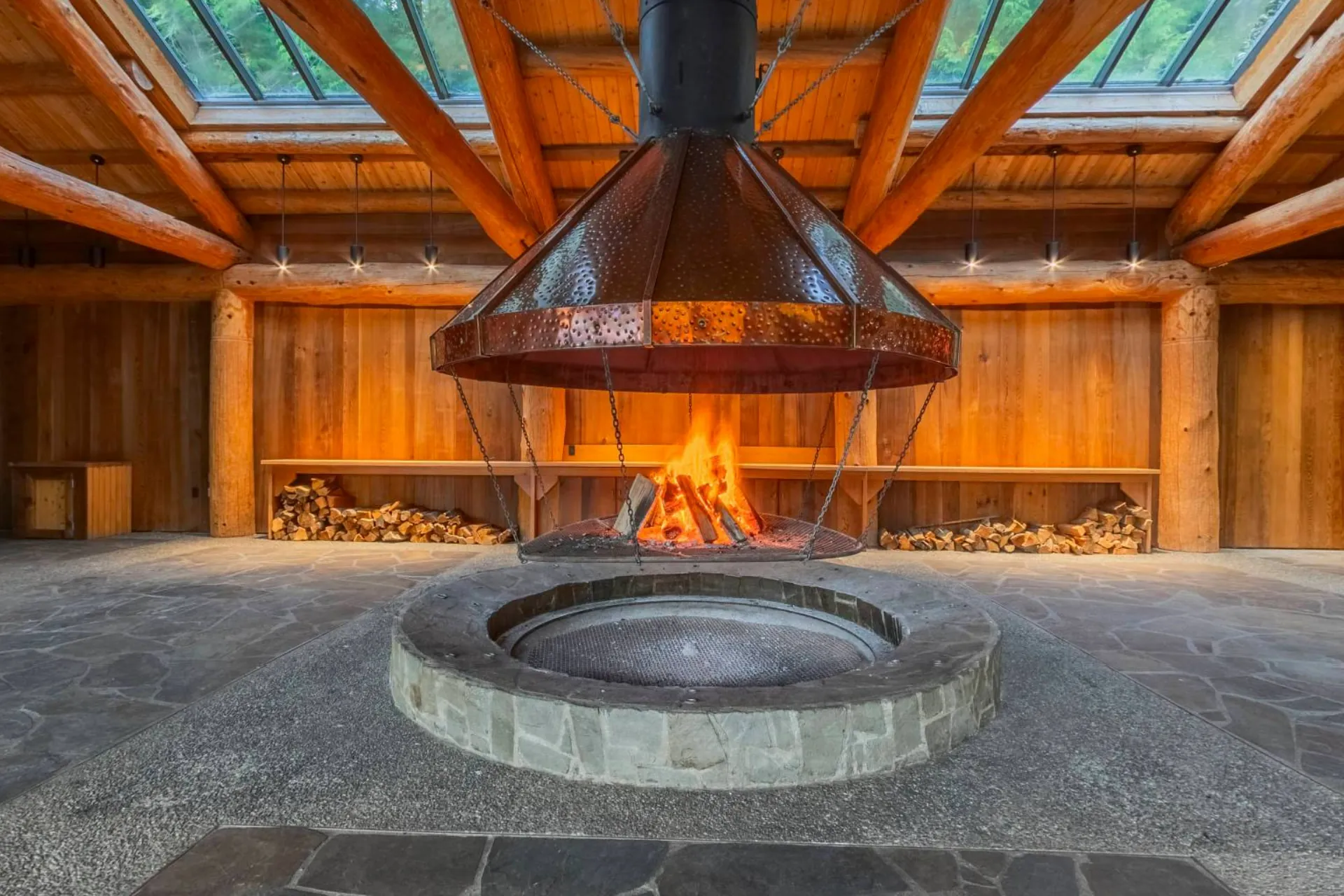 The longhouse fire burning under the hood, the stone hearth and the timber beams above