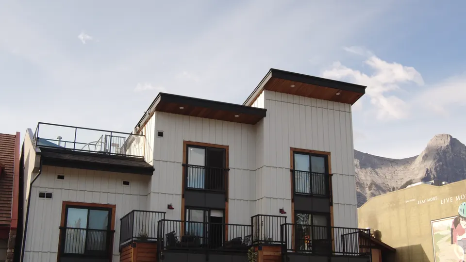 The white-clad suites with their rooftop deck, seen from the street against the mountainside