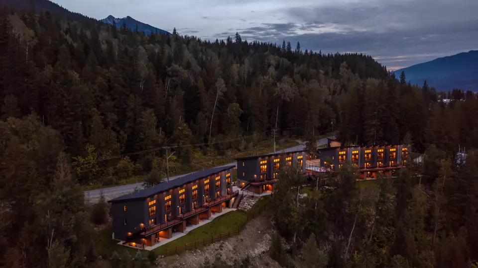 The suites lit at dusk on the bluff, the mountains behind