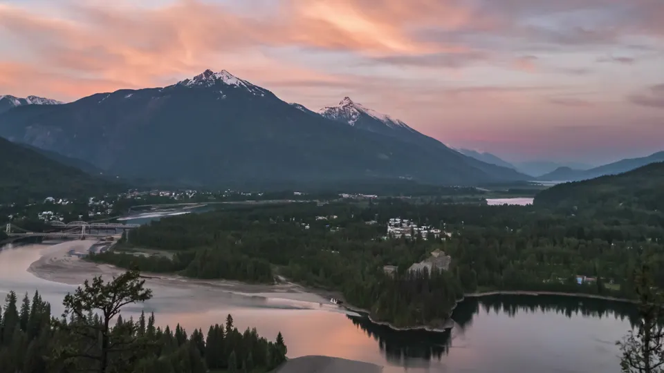 Sunset over a mountain lake outside Revelstoke, pink cloud above the peaks