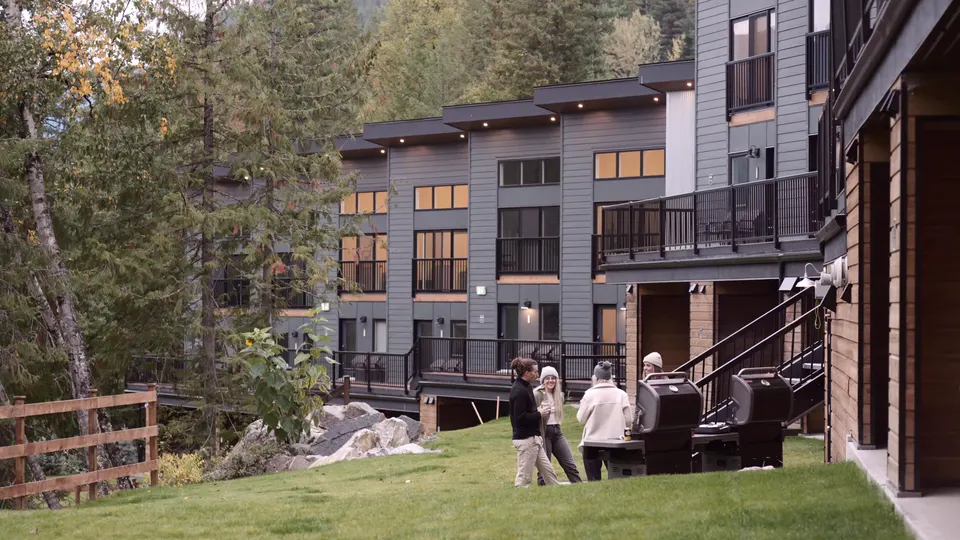 Guests on the lawn behind the suites, balconies above and the fire table by the fence