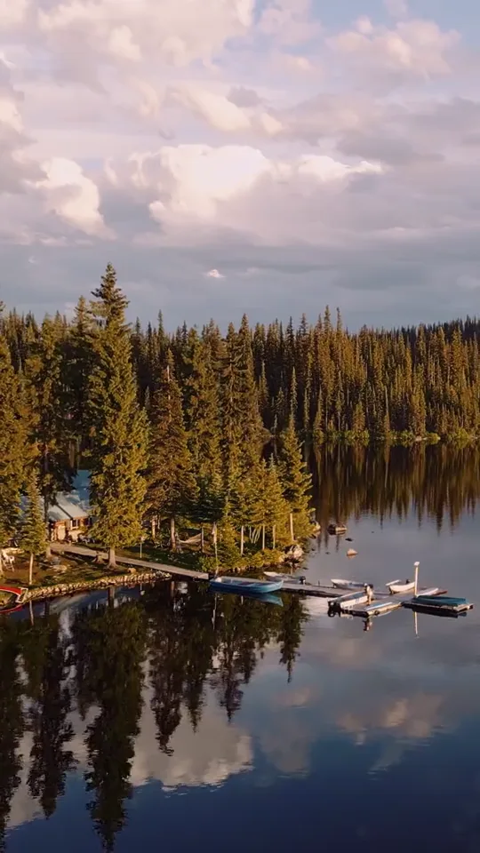 The lodge dock and boats from above, cloud reflected in the lake and forest to the horizon