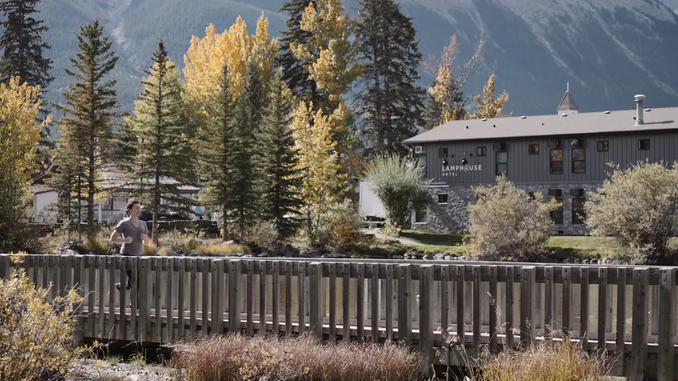 A guest crossing the footbridge over Policeman’s Creek towards Lamphouse, the hotel among yellow aspens