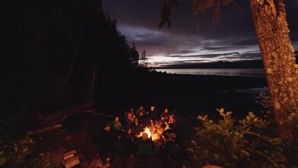 The group around the beach fire after dark, the last light going off the strait behind