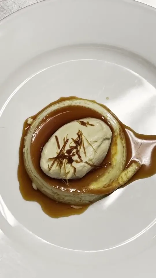 A plated dessert, a pale cream on a pastry base with a dark caramel sauce, on a white plate