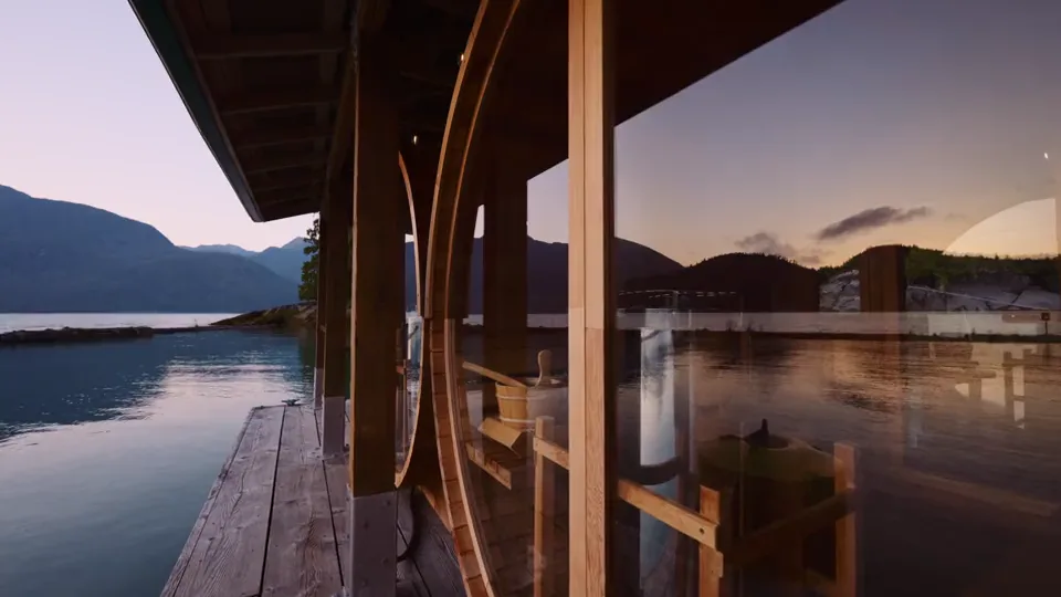 The floating dock at Knight Inlet Lodge at dusk, the sauna's timber posts and the still inlet reflecting the last light